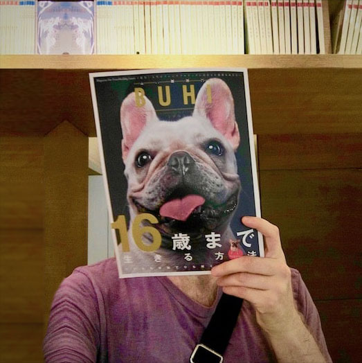 a man covering his face with a copy of BUHI magazine